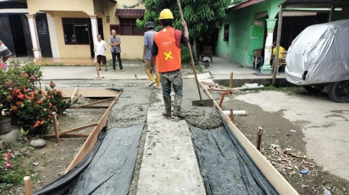 Petugas Dinas SDABMBK Medan sedang bekerja memperbaiki salah satu jalan gang yang rusak di Kecamatan Medan Marelan. Upaya ini menjadi program prioritas Wali Kota Rico Tri Putra Bayu Waas.