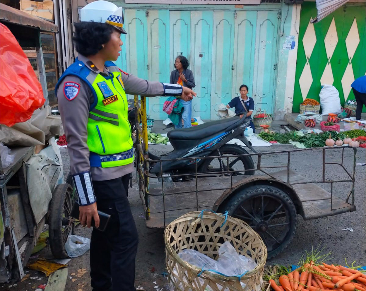 Petugas Sat Lantas Polres Pematangsiantar memberikan imbauan kepada pedagang pasar tumpah agar tidak menggelar dagangan di badan jalan Jalan Iman Bonjol, Senin (30/6).