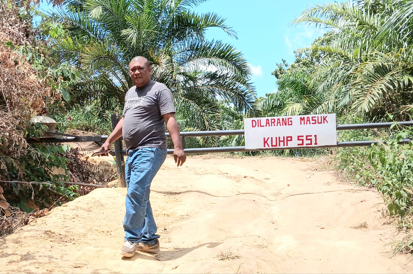 Aktivis berfoto di area bangunan portal terkunci bertuliskan &lsquo;Dilarang Masuk KUHP 551, diduga di kawasan hutan lindung.