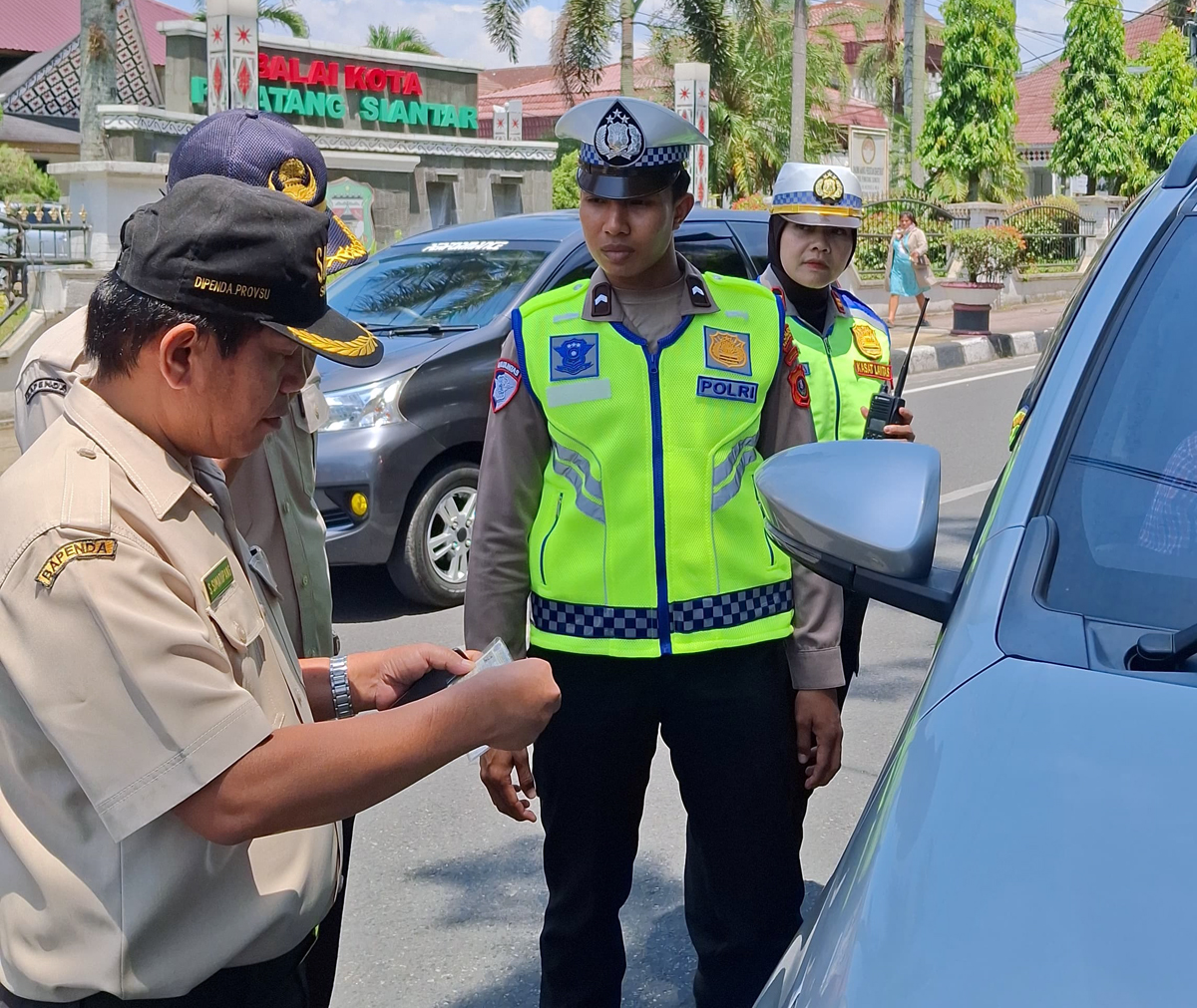 Petugas gabungan dari Satlantas Polres Pematangsiantar, KUPT Samsat, Jasa Raharja, dan BPKPD menjaring kendaraan yang belum bayar pajak saat razia di Jalan Merdeka, Rabu (30/7).