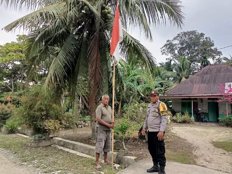 Bhabinkamtibmas Polesek AIPTU Sugianto saat memantau warga memasang bendera.