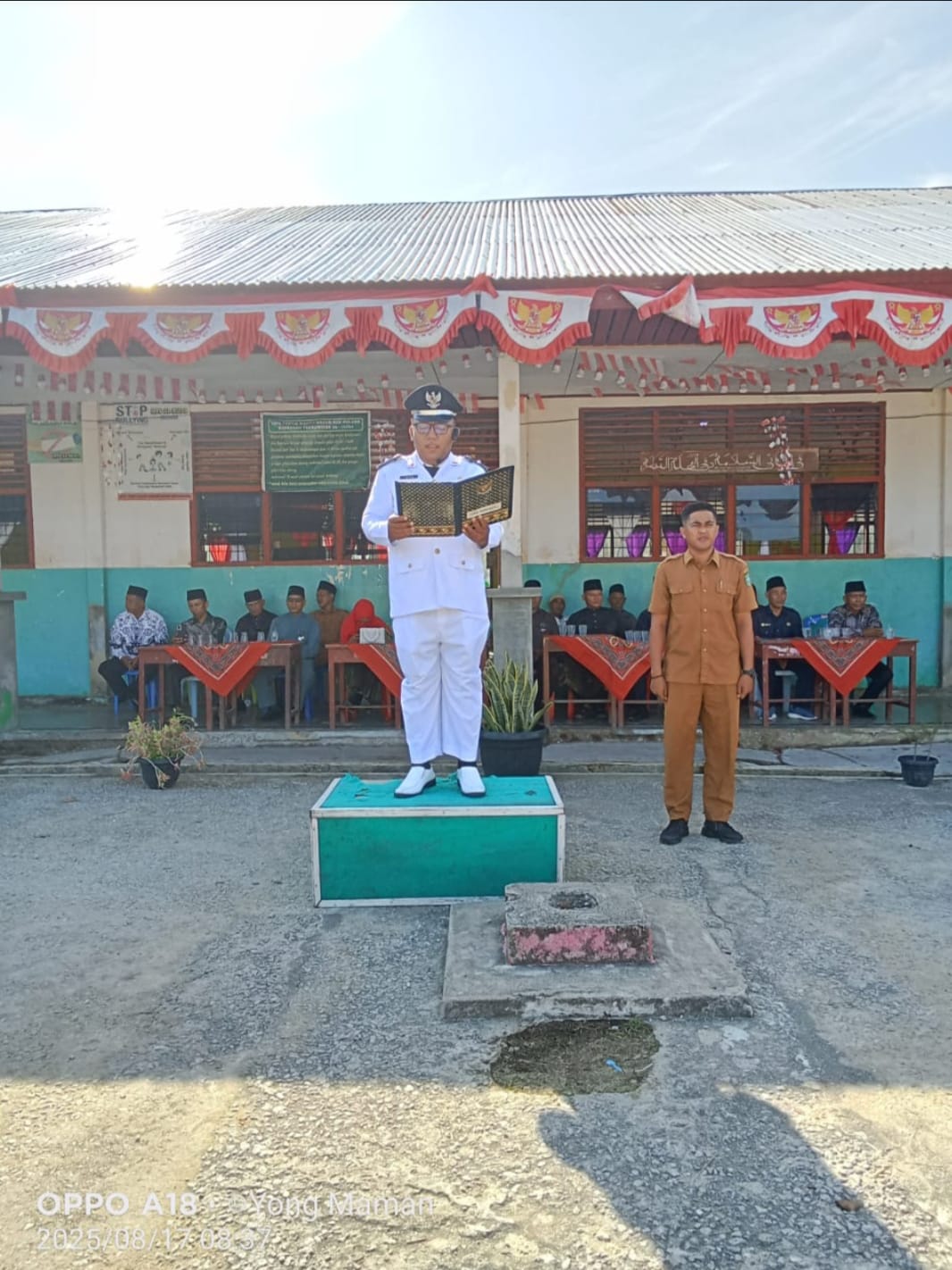 Pj Kades Kelebuk Edi Purma Irwan memimpin upacara HUT RI ke-80 di halaman MTs Al Huda bersama warga dan pelajar.