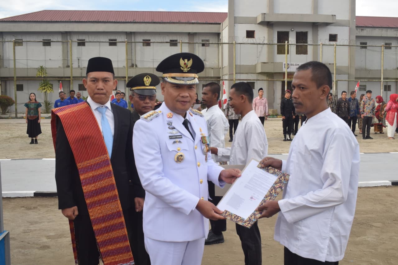 Bupati Humbahas Oloan didampingi Kepala Rutan Kelas IIB Humbahas Ucok Pangihutan Sinabang SH MH, menyerahkan remisi kepada salah satu warga binaan, Minggu (17/8), di halaman Rutan Humbahas.