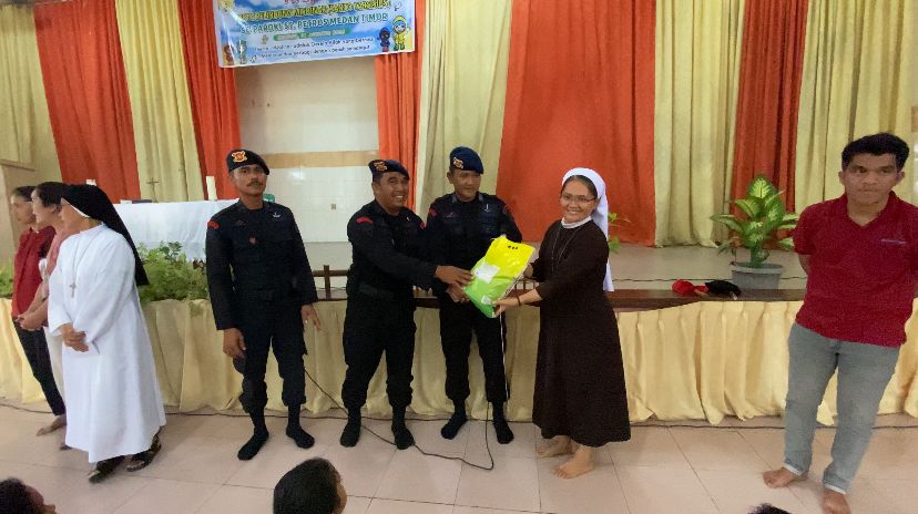 Personel Brimob Polda Sumut bersama OMK Gereja Santo Rafael membagikan sembako di Panti Asuhan SLB Santa Lucia, Deli Serdang, Minggu (31/8/2025).