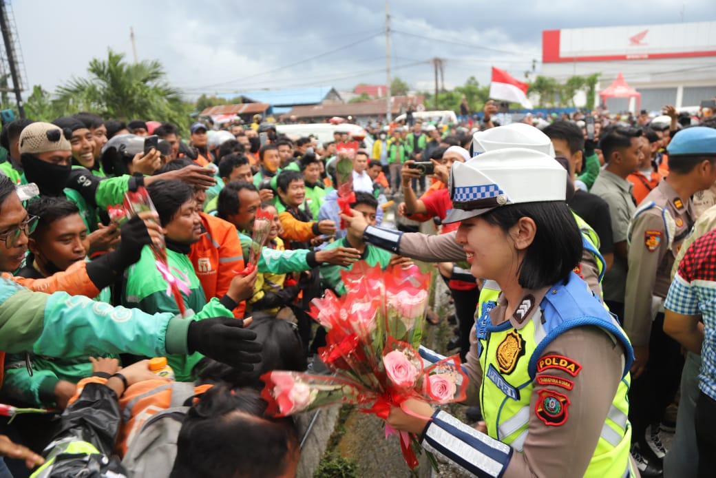 Polwan Polda Sumut membagikan bunga kepada driver ojol dalam aksi solidaritas GODAMS di Mapolda Sumut, Senin (1/9/2025).