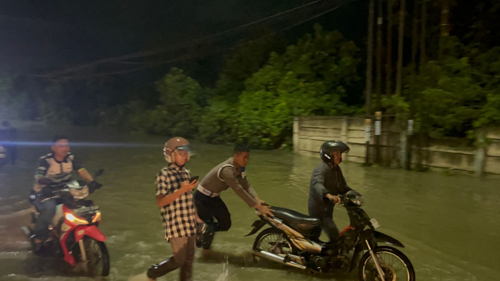 Personel Ditsamapta Polda Sumut turun langsung membantu warga dan mengatur arus lalu lintas saat banjir melanda Jalan Sisingamangaraja, Medan, Minggu malam (12/10/2025).