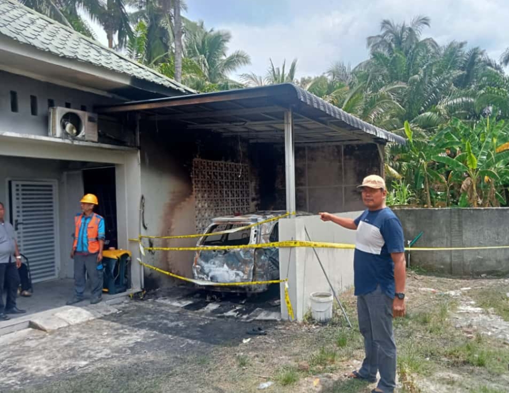 Petugas kepolisian memasang garis polisi di lokasi kebakaran rumah Een Hasibuan di Jalan Gambas, Kelurahan Siumbut Baru, Asahan, Jumat (17/10/2025) dini hari.