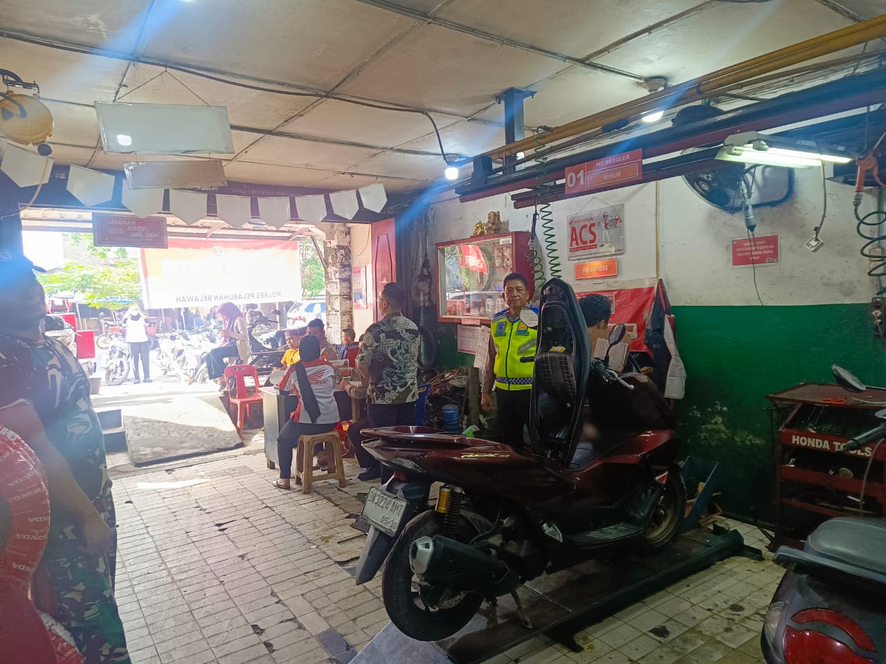 Petugas Polres Pelabuhan Belawan melakukan servis motor gratis bagi warga terdampak banjir di Bengkel Honda Harapan Servis, Belawan.