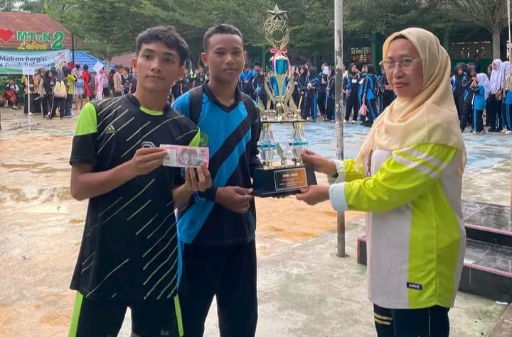 Kepala MTsN 2 Labuhanbatu Utara, Dra. Nurhabibah Harahap, menerima trofi juara umum Gebyar Liga Madrasah se-KKM 2025.
