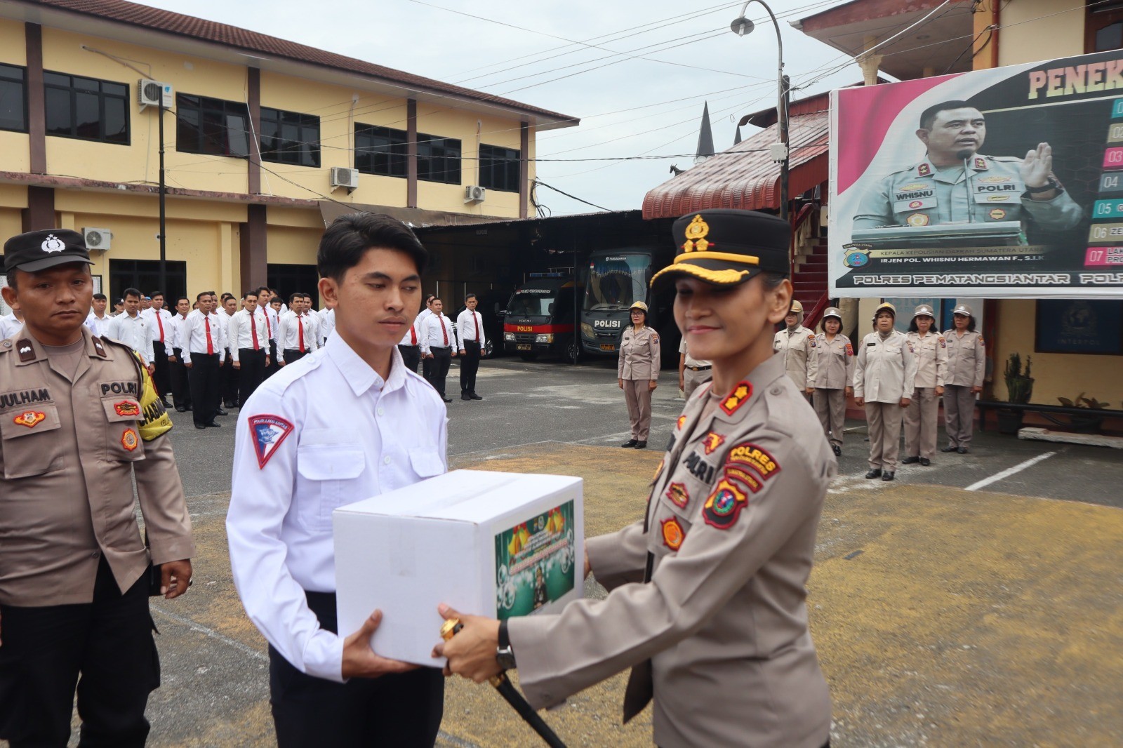 Kapolres Pematangsiantar AKBP Sah Udur Togi Marito Sitinjak menyerahkan bingkisan Natal secara simbolis kepada personel Polres, Selasa (16/12/2025).