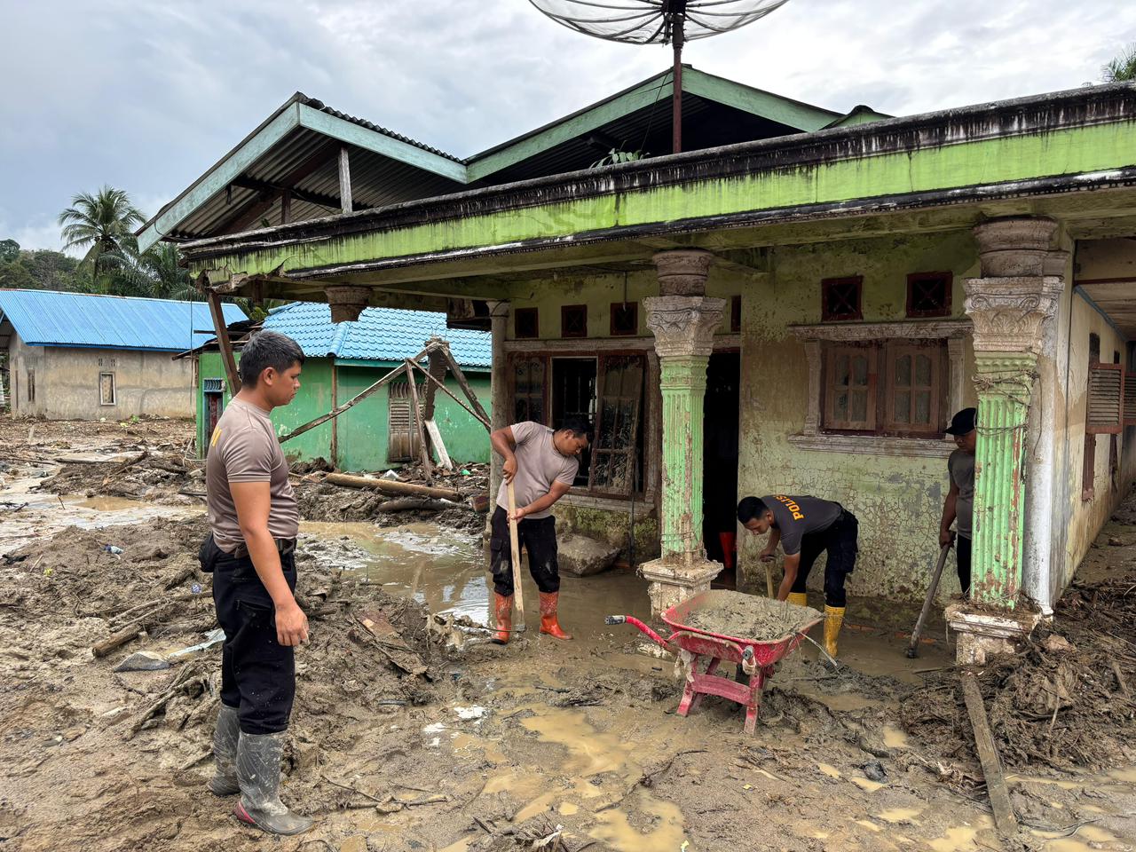 Personel Brimob Polda Sumatera Utara bersama TNI dan warga membersihkan lumpur serta sisa material banjir di permukiman Desa Huta Godang, Kecamatan Batang Toru, Tapanuli Selatan.