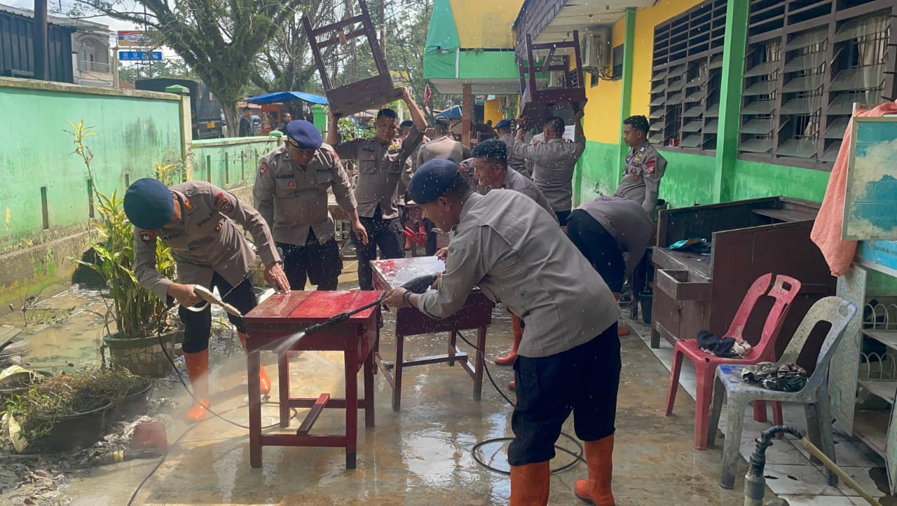Personel Brimob Batalyon A Polda Sumut membersihkan lumpur dan material sisa banjir di SMP Negeri 1 Tanjung Pura, Kabupaten Langkat, Senin (29122025).