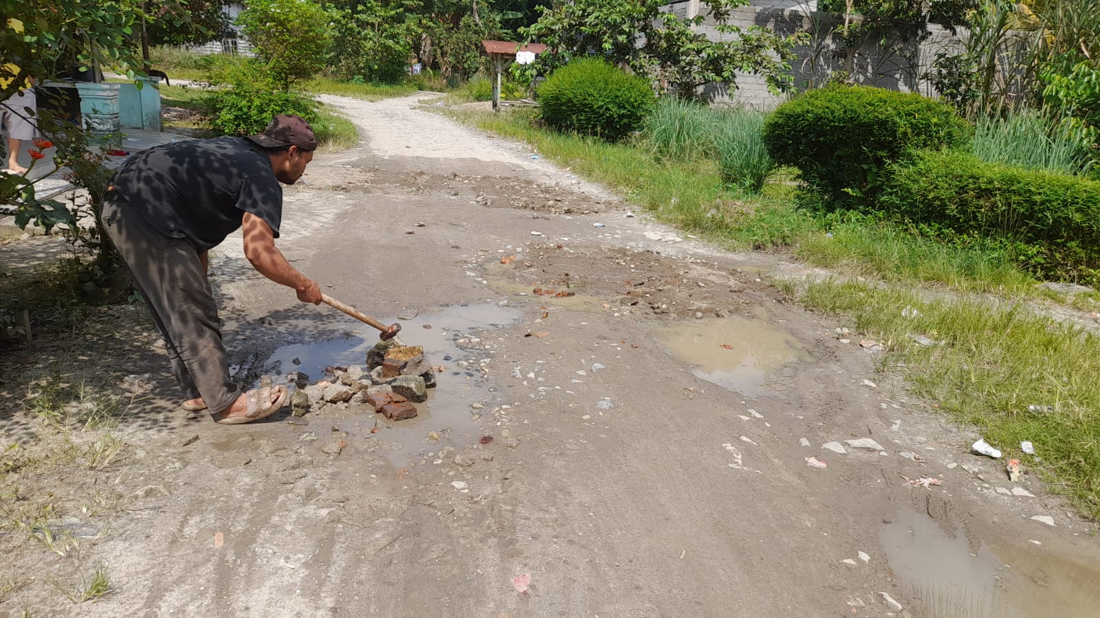 Warga Desa Sidua-Dua bergotong royong menimbun jalan berlubang di Dusun V, Labuhanbatu Utara, sebagai upaya sementara menjaga keselamatan pengguna jalan.