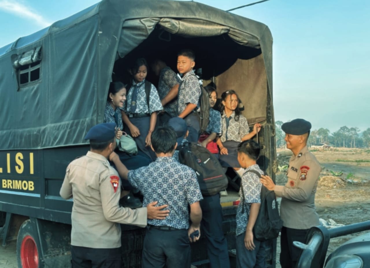 Personel Brimob Polda Sumut mengantar anak-anak sekolah terdampak banjir bandang di Desa Garoga, Kecamatan Batang Toru, Tapanuli Selatan.