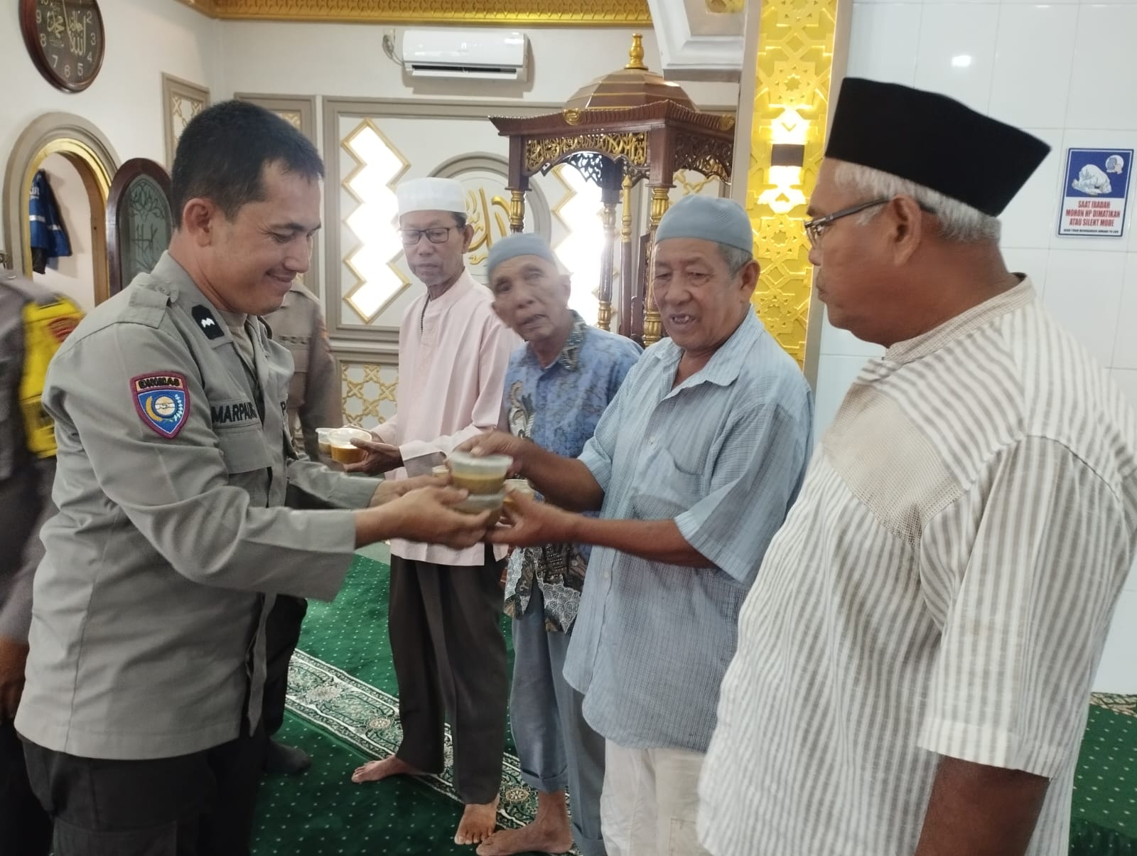 Personel Polres Tanjungbalai membagikan 100 cup bubur kepada jamaah Masjid Nurul Ikhwan dan Masjid Nurul Huda saat menjelang waktu berbuka puasa, Minggu (1/3/2026).