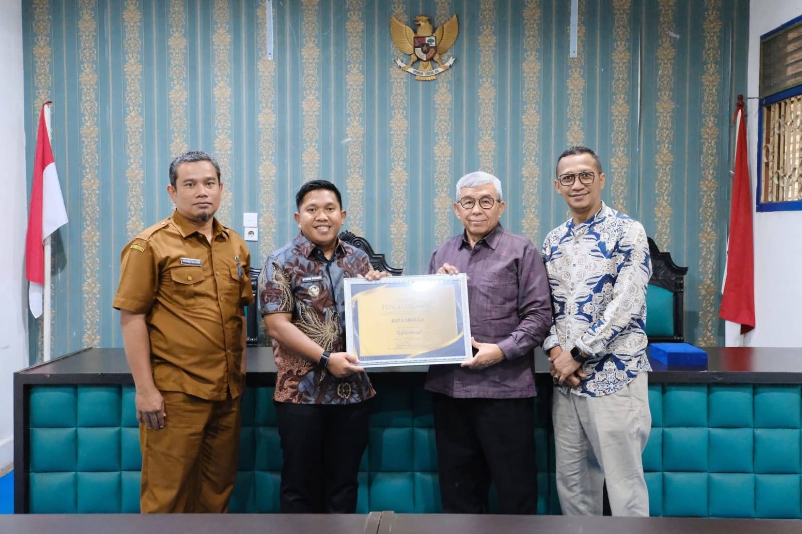 Wali Kota Sibolga Akhmad Syukri Nazry Penarik didampingi Plt Kadiskominfo Romatua Hasonangan Panjaitan menerima penghargaan dari Ketua Komisi Informasi Provinsi Sumatera Utara di Medan. 