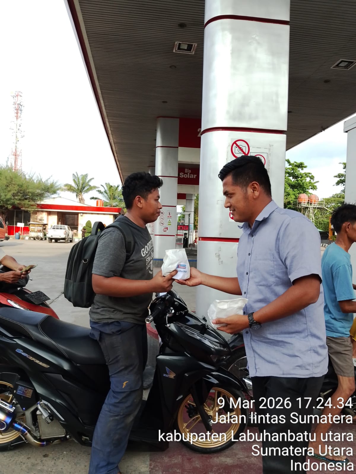 Petugas SPBU Aek Kanopan membagikan takjil kepada pengendara yang melintas di depan SPBU.   