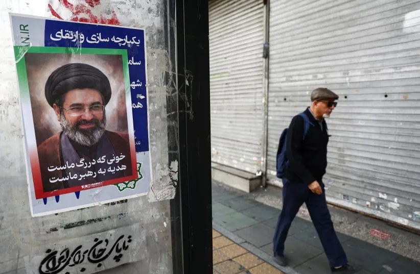 Seorang warga melintas di depan poster bergambar Mojtaba Khamenei di Teheran, Iran, 22 Maret 2026. Isu dugaan orientasi seksualnya memicu sorotan global di tengah kerasnya kebijakan anti-LGBTQ+ Iran.