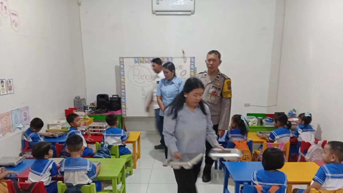 Petugas kepolisian memonitor distribusi 121 paket Makanan Bergizi Gratis (MBG) kepada murid TK Nazaret di Pematangsiantar.