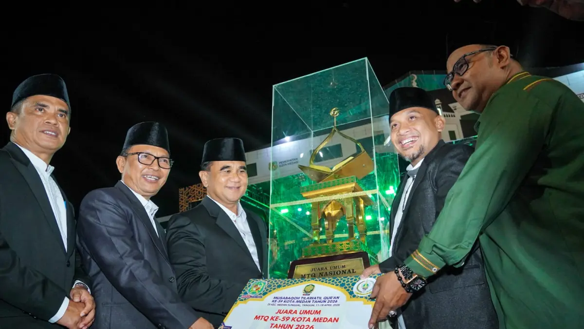 Asisten Pemerintahan Setda Kota Medan M. Sofyan menyerahkan piala juara umum MTQ ke-59 kepada Camat Medan Selayang pada penutupan di Jalan Gatot Subroto, Sabtu (18/4/2026) malam.