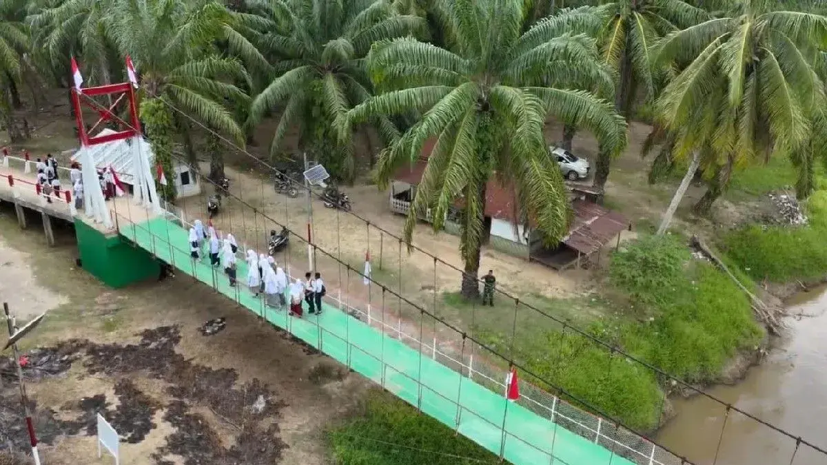 Sejumlah pelajar melintas di Jembatan Garuda yang telah selesai diperbaiki TNI di Desa Rasau, Kecamatan Torgamba, Labuhanbatu Selatan.
