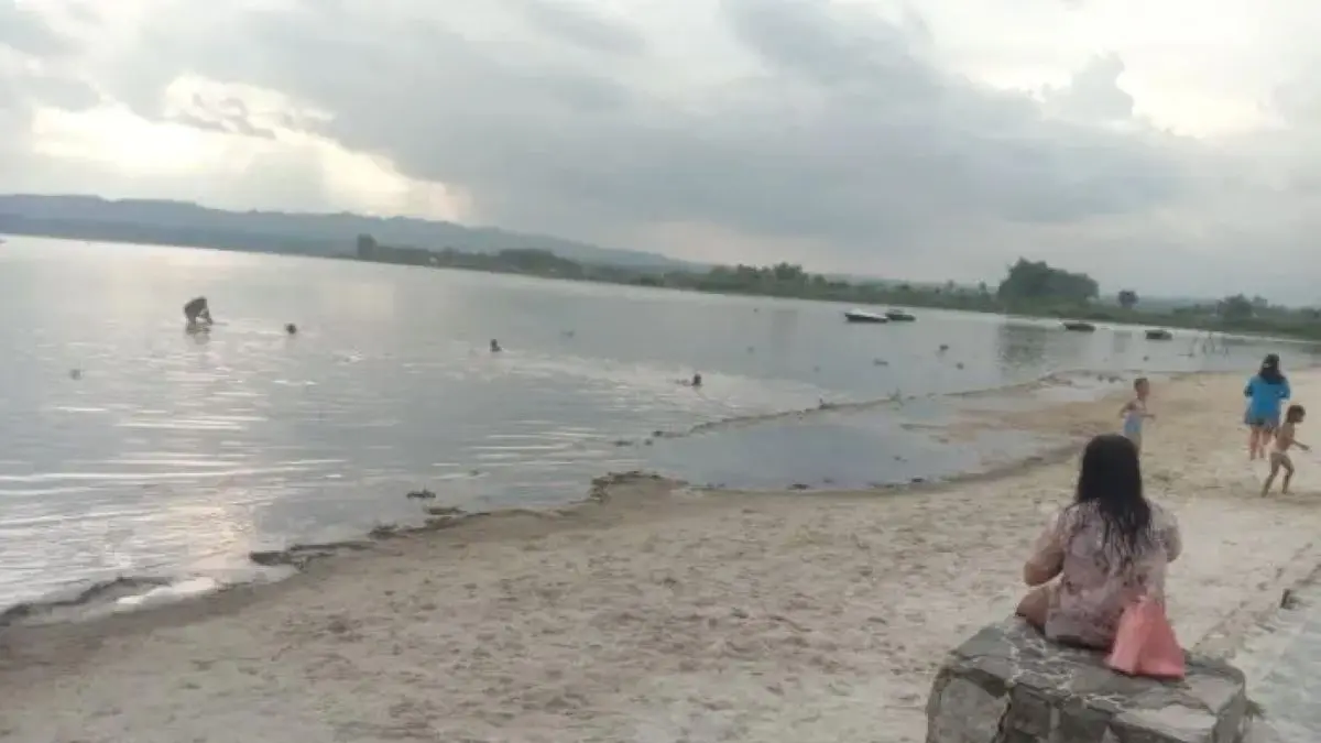 Pengunjung menikmati suasana Pantai Pasir Putih Parparean di kawasan Danau Toba yang mengalami kenaikan permukaan air akibat curah hujan tinggi.