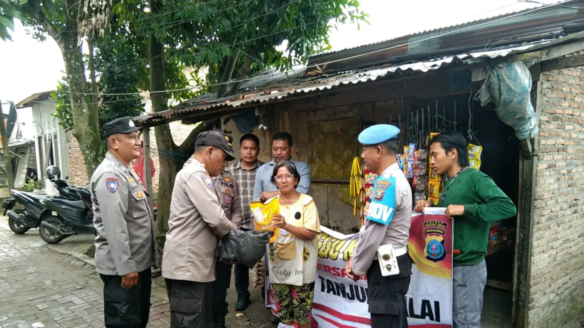  Personel Polres Tanjungbalai menyerahkan bantuan sosial kepada warga saat kegiatan Minggu Kasih di Komplek Mujur, Kelurahan Tanjungbalai Kota III. 