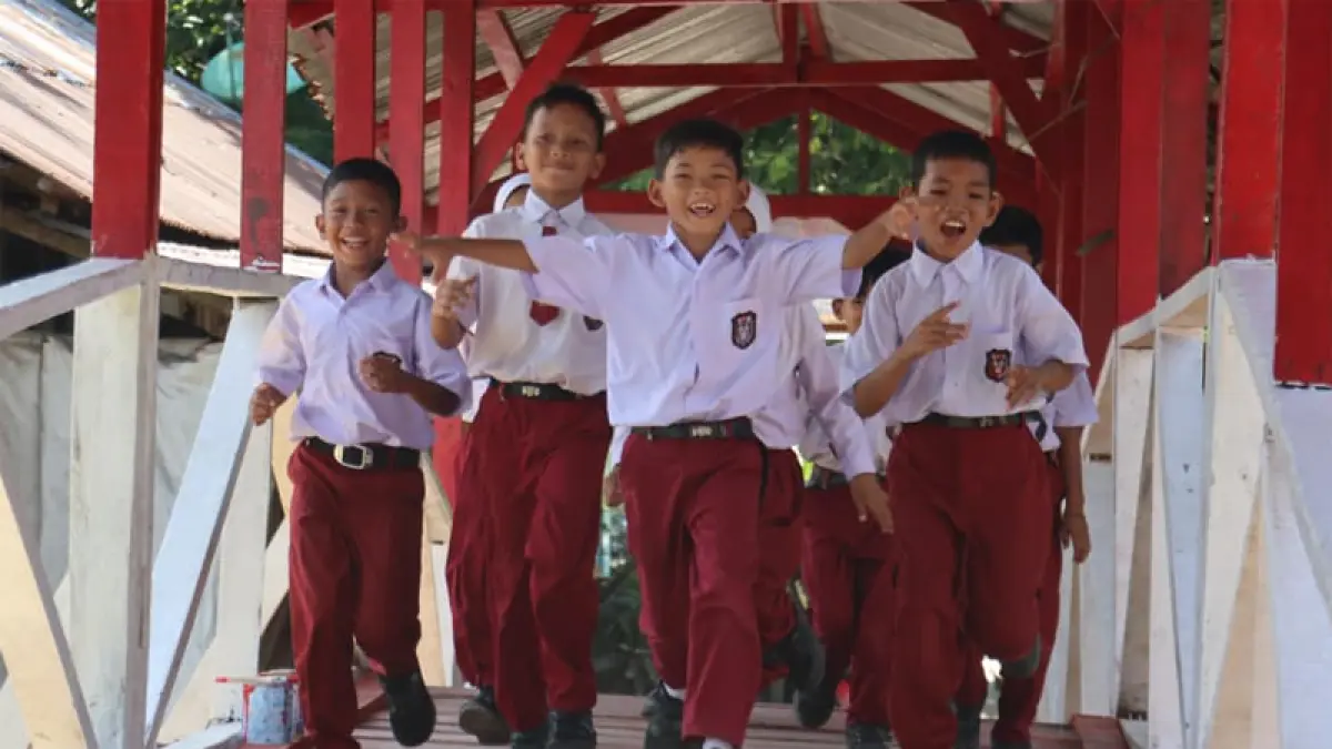 Pelajar Sekolah Dasar terlihat gembira melintasi jembatan merah putih Kelurahan Sei Merbau, Kecamatan Teluk Nibung, Kota Tanjungbalai.