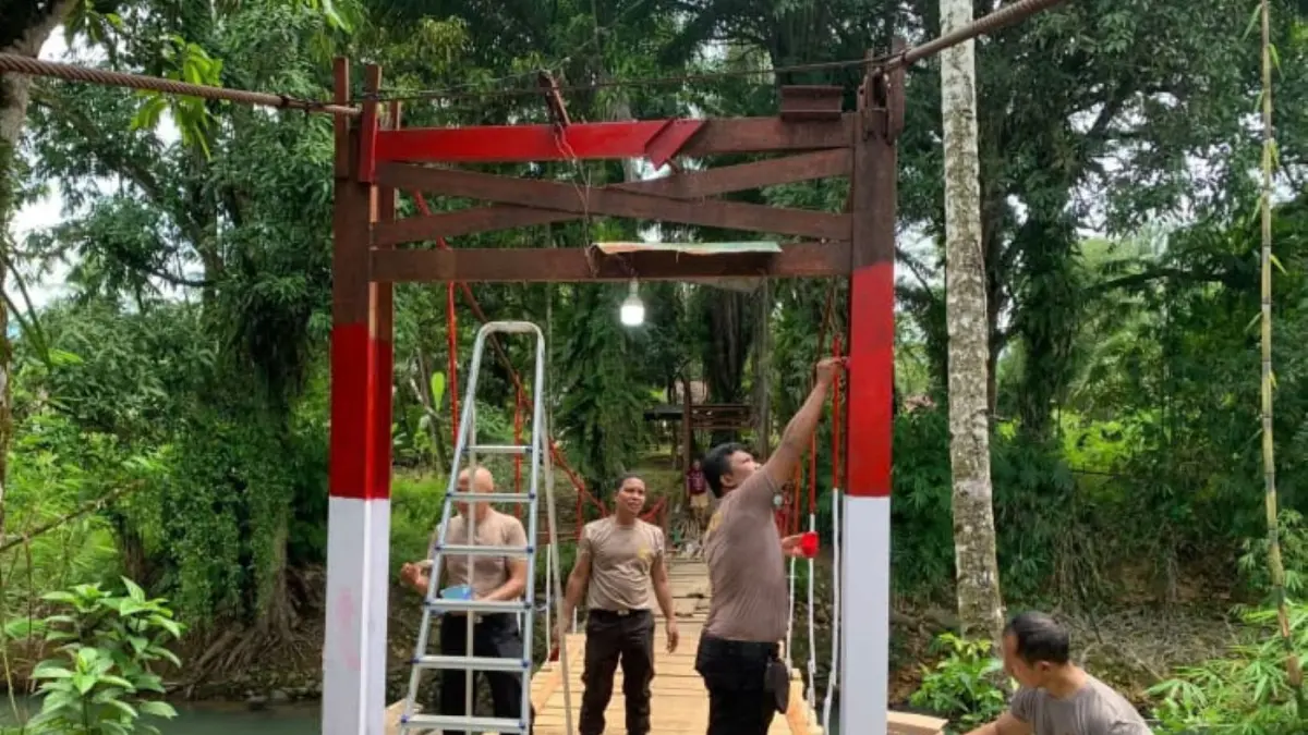 Personel Polsek Sibabangun bersama warga merevitalisasi dan memperbaiki jembatan gantung di Lingkungan IV Kelurahan Sibabangun, Kabupaten Tapanuli Tengah.