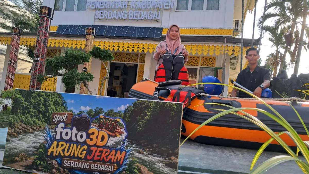 Pemandu Paviliun Serdang Bedagai berfoto di depan boat arung jeram Bah Bolon di PRSU 2026 di Medan. Destinasi tersebut menjadi salah satu yang paling banyak ditanyakan selama pameran berlangsung. (Dame Ambarita/MetroDaily)