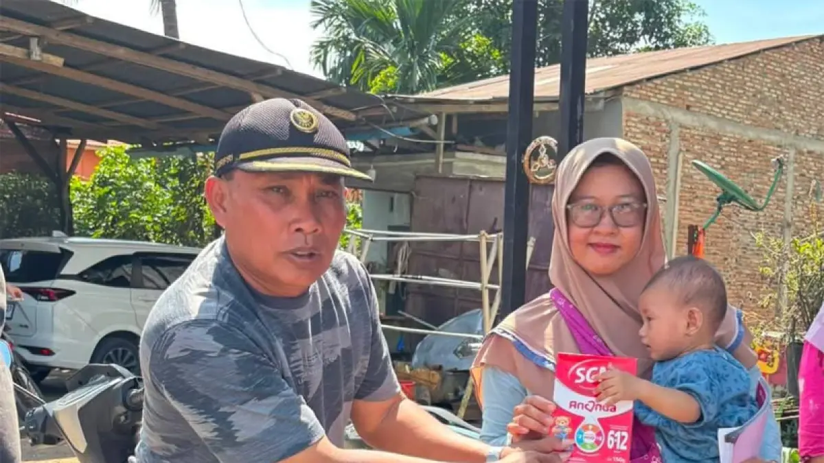 Kepala Desa Gunung Melayu, Sahran Tanjung, menyerahkan bantuan gizi tambahan berupa susu untuk balita dan ibu hamil.&nbsp;