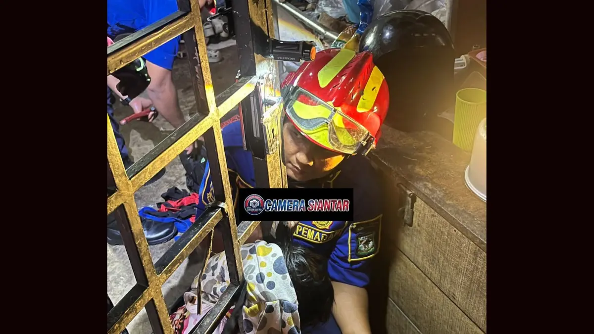 Tim Disdamkarmat Kota Pematangsiantar mengevakuasi seorang bocah perempuan berusia empat tahun yang kepalanya terjepit di sela-sela terali pintu besi rumahnya di Kelurahan Tomuan, Kecamatan Siantar Timur, Rabu (29/7/2026).