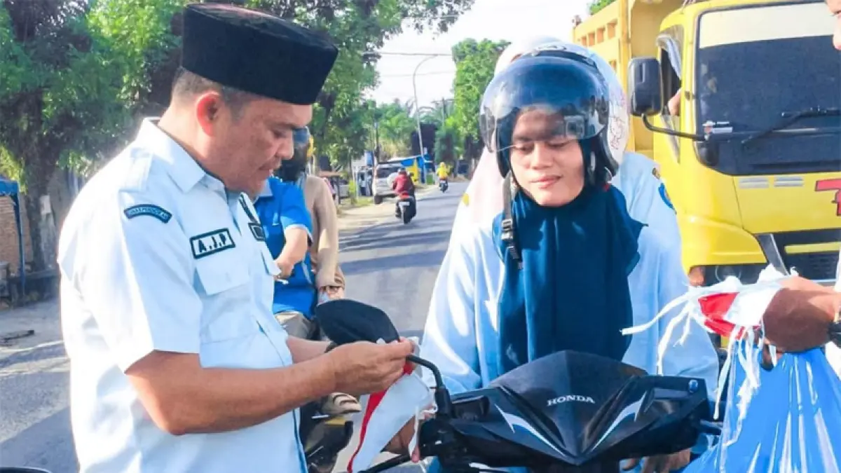 Plh Sekda Labuhanbatu Abdi Jaya Pohan saat memberikan bendera kepada pengendara secara gratis.
