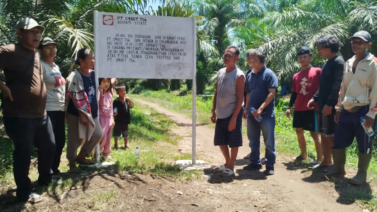 Warga Marbau menunjukkan plang pembatasan akses yang dipasang PT SMART Tbk Kebun Adipati dan dinilai mempersempit badan jalan menuju permukiman serta perkebunan warga. 