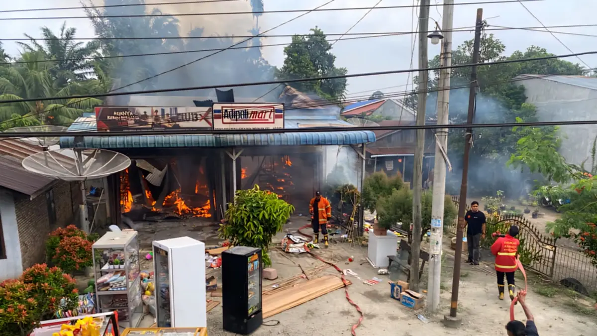 Tim damkar melakukan pemadaman api yang menghanguskan dua ruko di Air Batu.