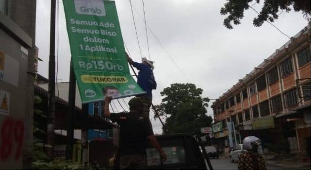 Penertiban spanduk iklan Grab di tiang telepon Jalan Kartini Pematangsiantar, Senin (11/10). (f: metro/matius)