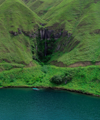 Air Terjun Sitiris-tiris Samosir yang diapit bukit hijau.