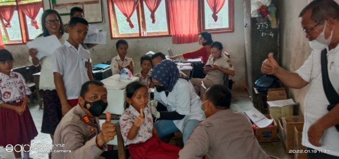 Foto: (Zatam/New Tapanuli) Kapolsek Pinangsori mendampingi salah seorang siswa yang hendak di vaksin.