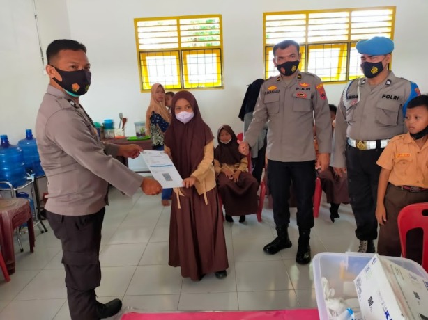 Personil Polres Labuhanbatu menyerahkan sertifikat vaksin kepada Murid SD 02 Bilah Barat.