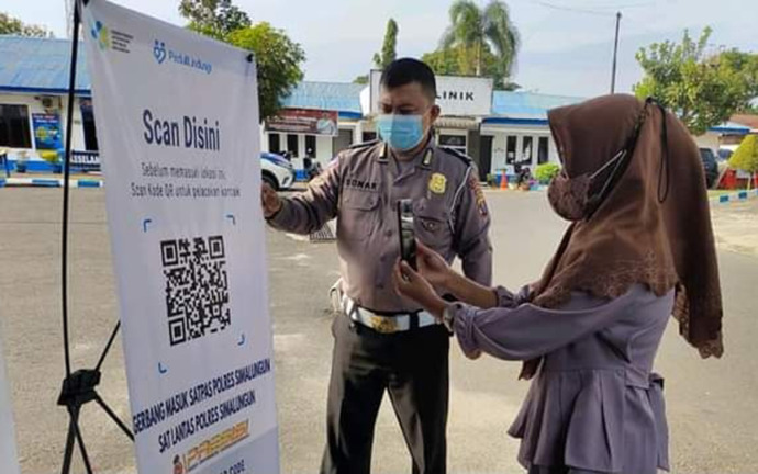 Scan barcode aplikasi PeduliLindungi di Kantor Satpas Polres Simalungun.
