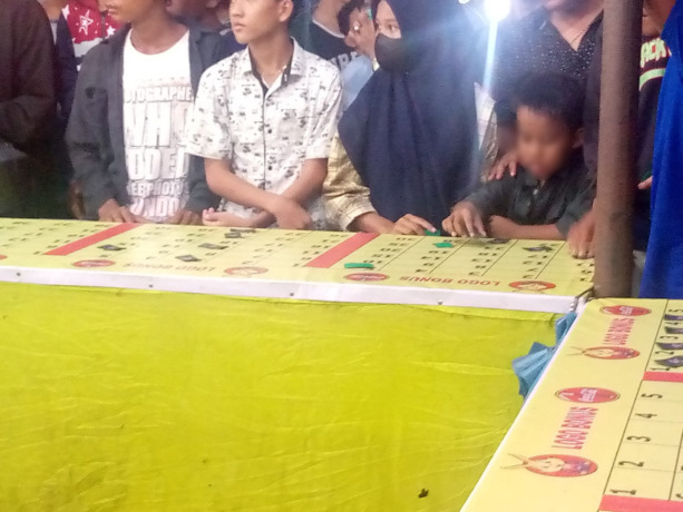 Anak terlihat di gelanggang permainan berhadiah rokok di Pasar Malam Rambung Merah.