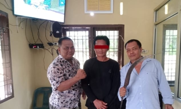 Pelaku pembacok kades, diapit polisi saat diamankan di Polsek.