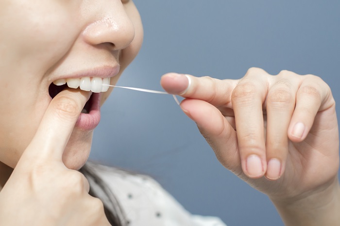 Ilustrasi seseorang menggunakan dental floss. (vecteezy.com)
