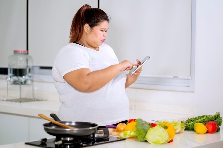 Ilustrasi seorang wanita obesitas yang melihat dan mengikuti panduan menu sehat melalui gawainya.