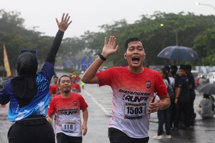 Ilustrasi para pelari yang tampak tetap semangat dan ceria walau hujan mengguyur saat Bhayangkara Run 2024. Olahraga saat hujan bisa menjadi pilihan yang menyegarkan dan menantang.