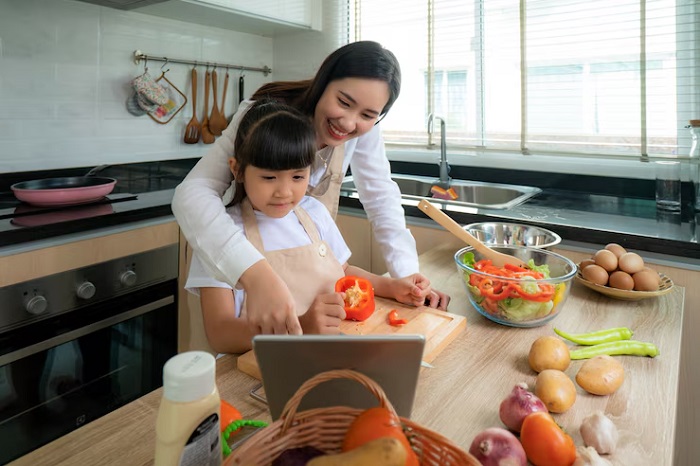 Ilustrasi seorang anak perempuan dan ibunya yang memilih bersama menu salad di tablet untuk mempersiapkan bekal di sekolah.