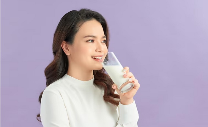 Ilustrasi seorang wanita yang minum minuman fiber yang membantu meningkatkan asupan serat harian.