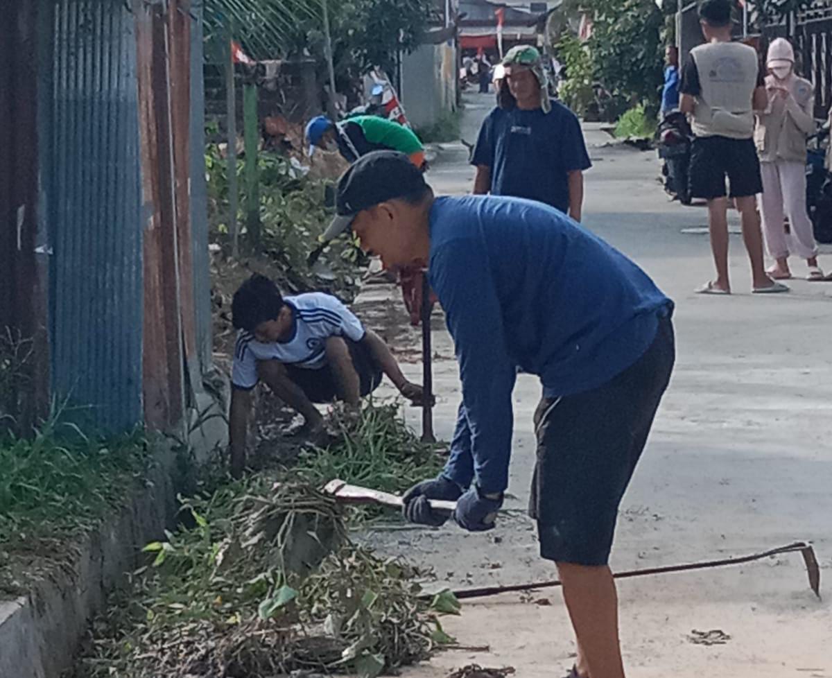 ANGKAT SUMBATAN: Warga RT 29 Kelurahan Tanjung Laut Indah membersihkan parit dari rumput liar yang bisa membuat laju aliran air terhambat.
