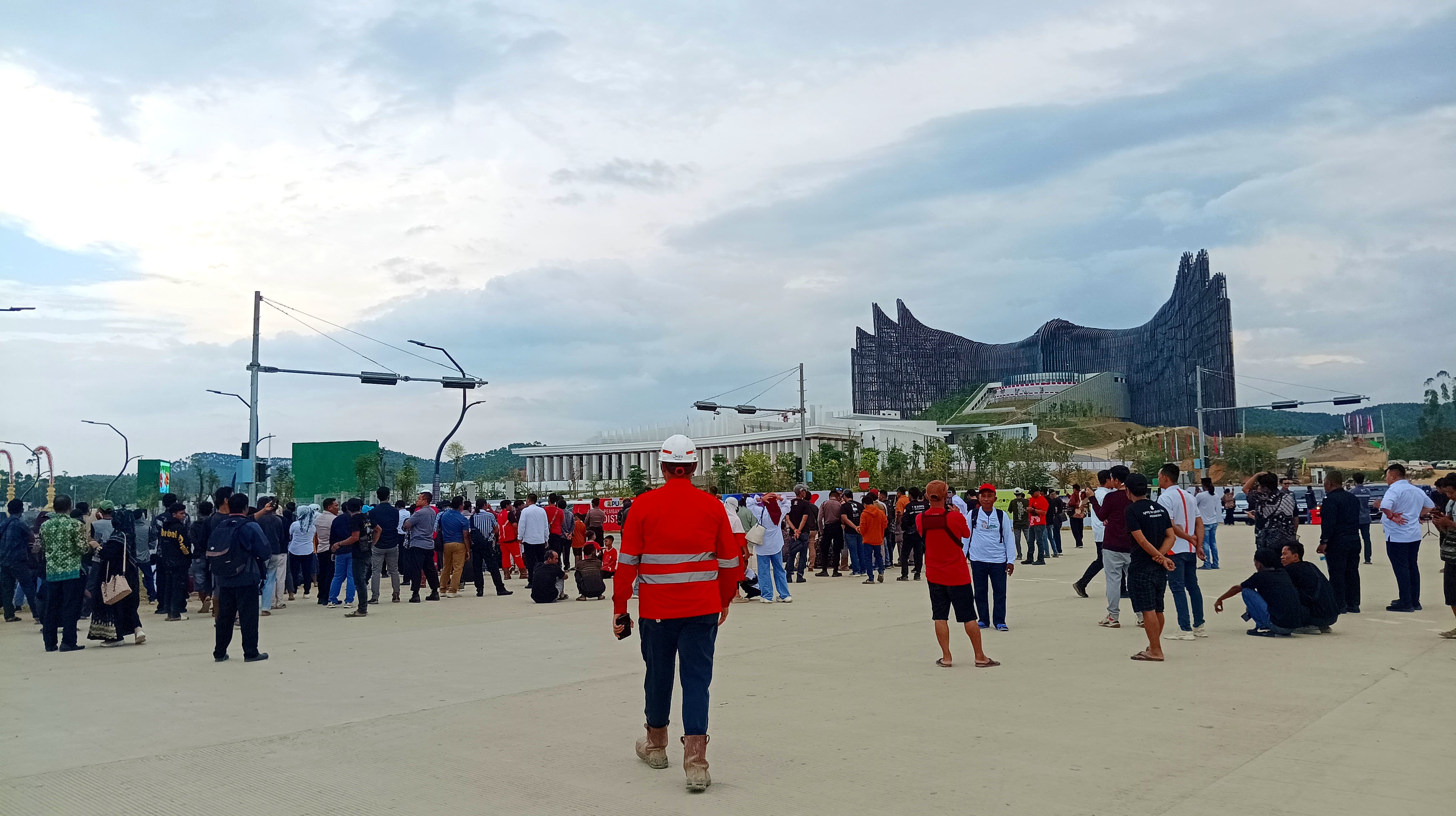 BERSAMA: Warga dan para pekerja sedang menyaksikan upacara HUT Kemerdekaan RI ke 79 dari luar Istana Garuda. (FOTO: SYAHRUL)