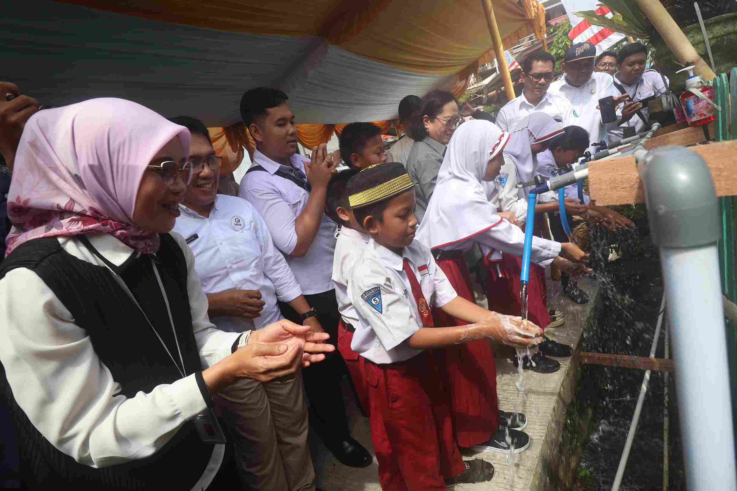 MENGALIR: Anak-anak sekolah langsung mencuci tangan dari air hasil treatment di Gunung Sari Ulu. (Foto: Anggi/KP)